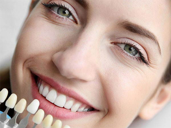 A woman with bright eyes, smiling at the camera, showcasing her teeth with a dental hygiene product.
