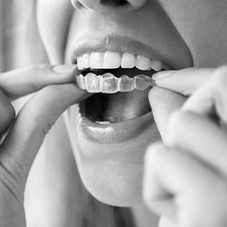 The image shows a person with their mouth open, holding a toothbrush with toothpaste on it, while looking directly at the camera.