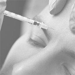 An image depicting a person receiving an injection into their forehead by a medical professional using a syringe.