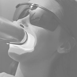 A person wearing sunglasses appears to be blowing into a device with their mouth, which could possibly be a microphone or a similar object.