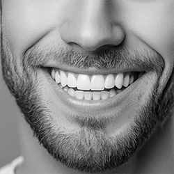 The image shows a man with a beard smiling broadly towards the camera.