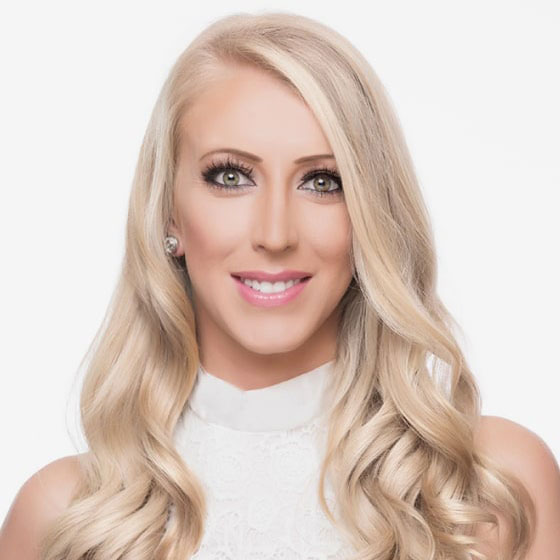 A smiling woman with long blonde hair and makeup, posing against a white background.