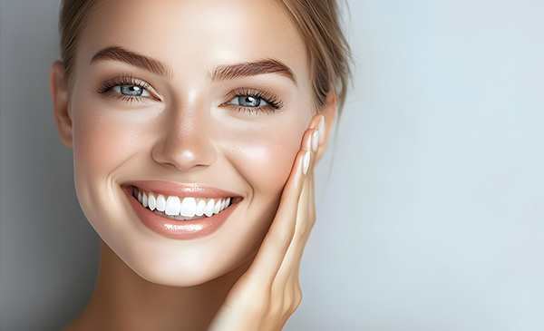 The image shows a woman with a radiant smile, looking directly at the camera, against a neutral background.