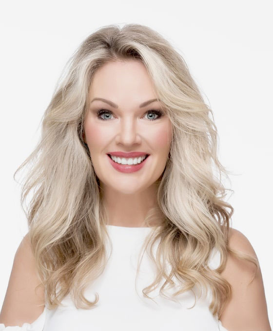 Woman with blonde hair, wearing white top, smiling at camera.