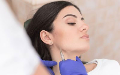 A woman receiving a facial treatment with a needle at a spa or beauty salon, attended by a professional.