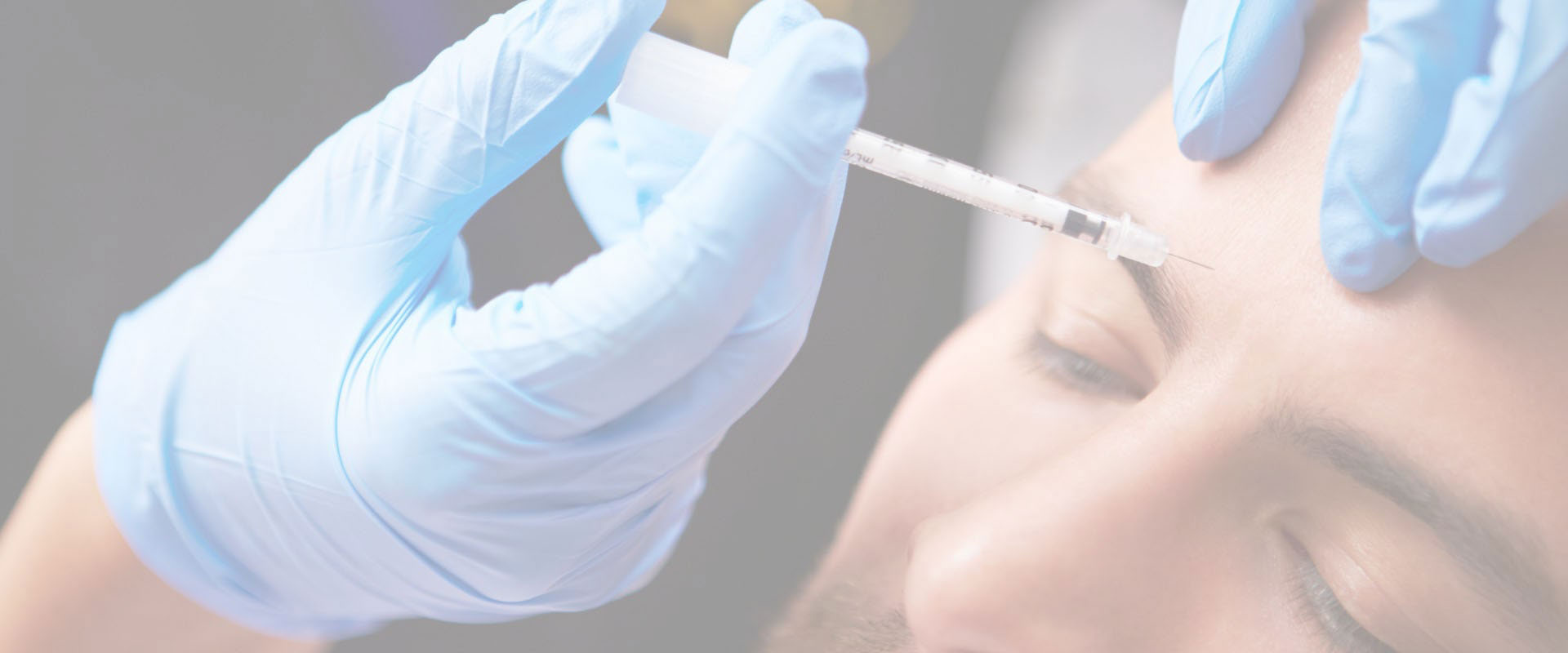 The image shows a person receiving a vaccination, with a syringe being used by someone wearing gloves and a face mask.