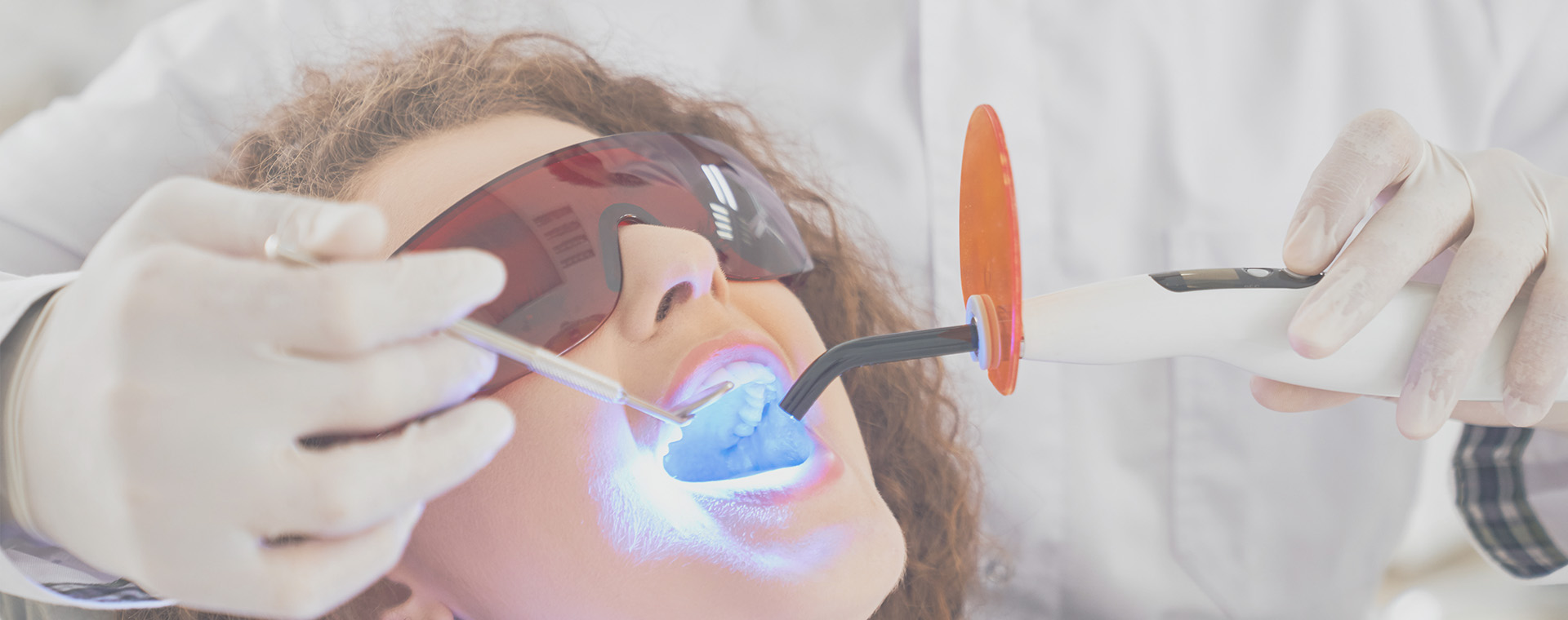 A woman receiving dental treatment with a dentist using a specialized device.