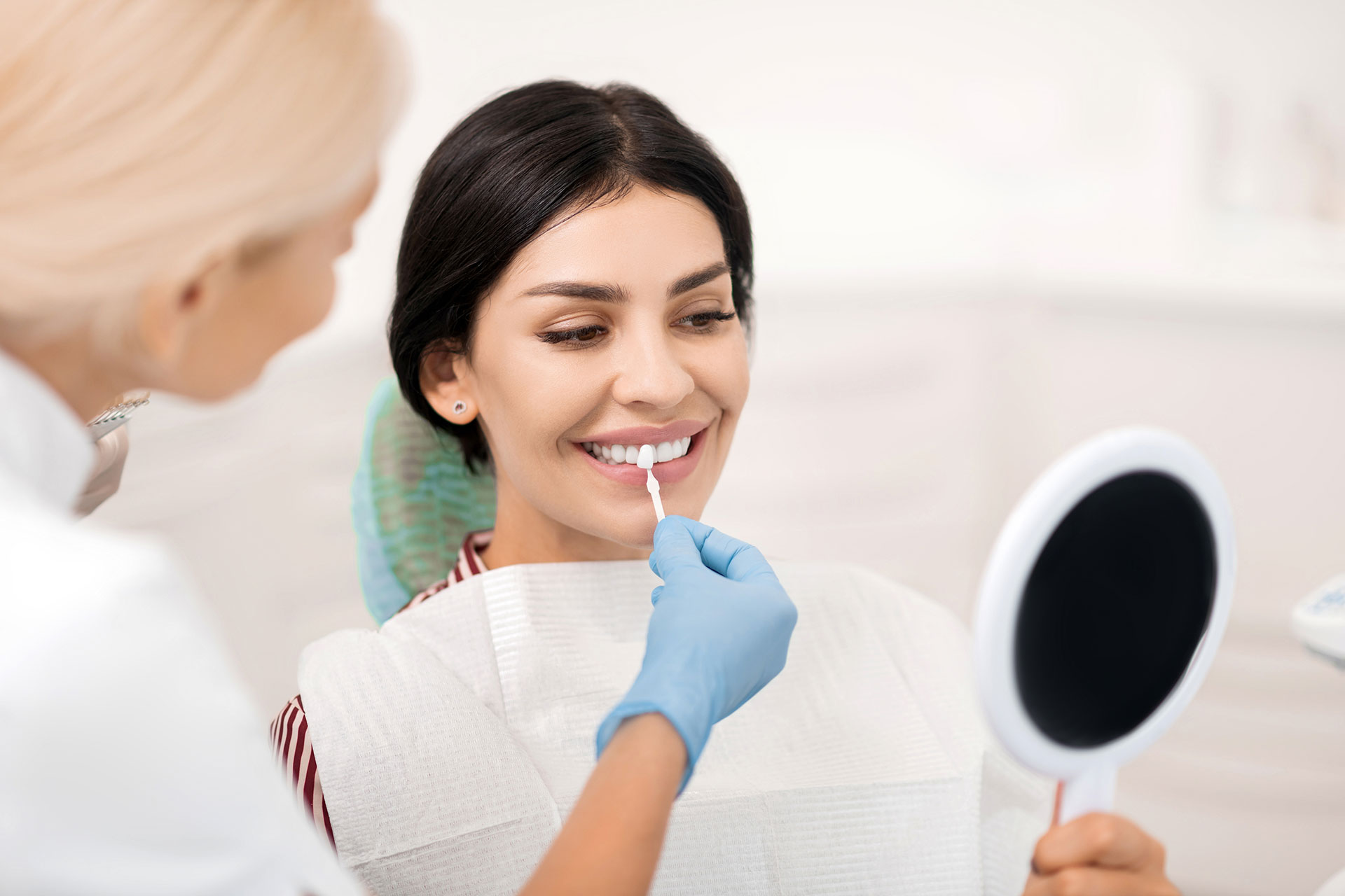 Woman receiving dental care with dentist using mirror to examine mouth.