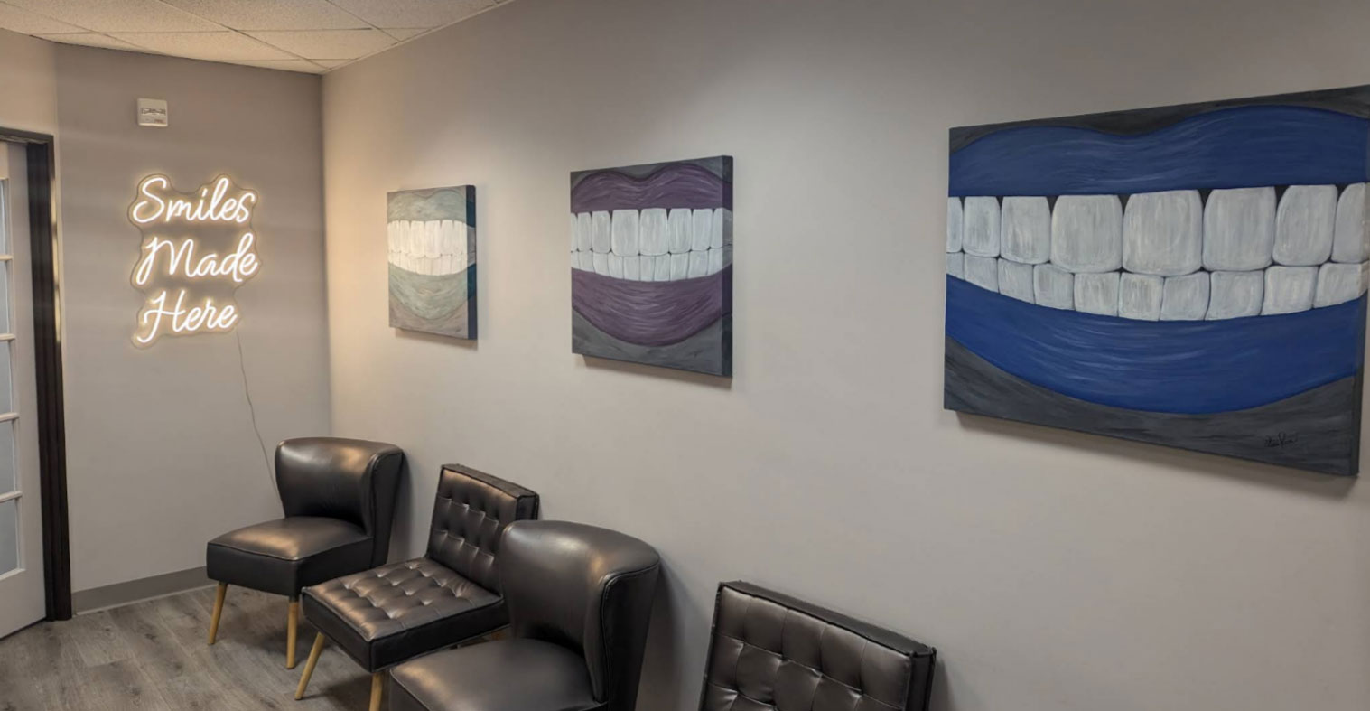 The image shows a wall with three framed paintings hanging at different heights, each depicting a toothy smile with varying shades of blue and purple backgrounds.