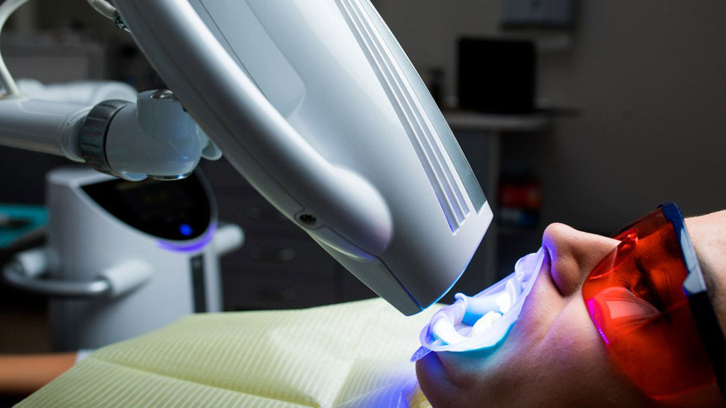An individual undergoing dental treatment with a laser device, viewed through a digital overlay.