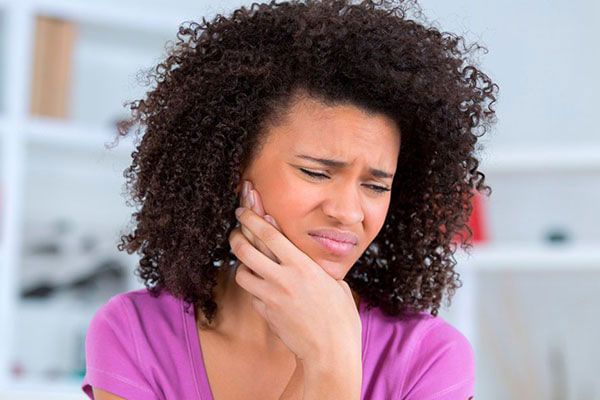The image shows a person with curly hair holding their head with one hand, while looking concerned or distressed.
