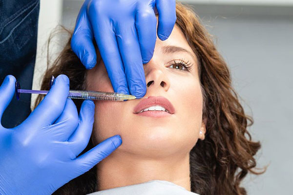 Woman receiving cosmetic treatment with a syringe, under the supervision of a professional in a clinical setting.